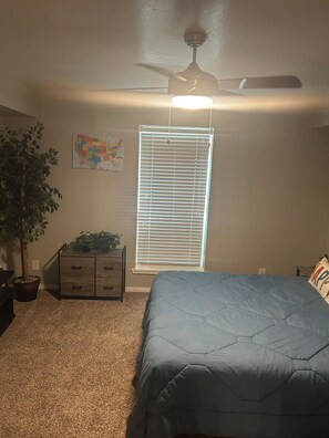 A bedroom with a bed, a ceiling fan, a window with blinds, a dresser, a potted plant, and a map on the wall. - Relax & Recharge  in this Spacious Apartment / near the Medical Center & NRG! (Houston)