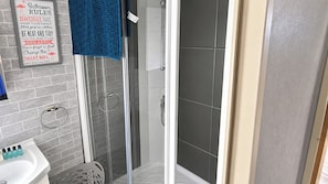 Un baño con ducha, un perchero para toallas y un cartel con las normas del baño.
