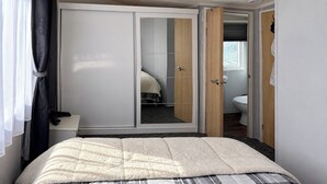 Una camera da letto con un letto, un armadio e un bagno parzialmente visibile attraverso una porta aperta.