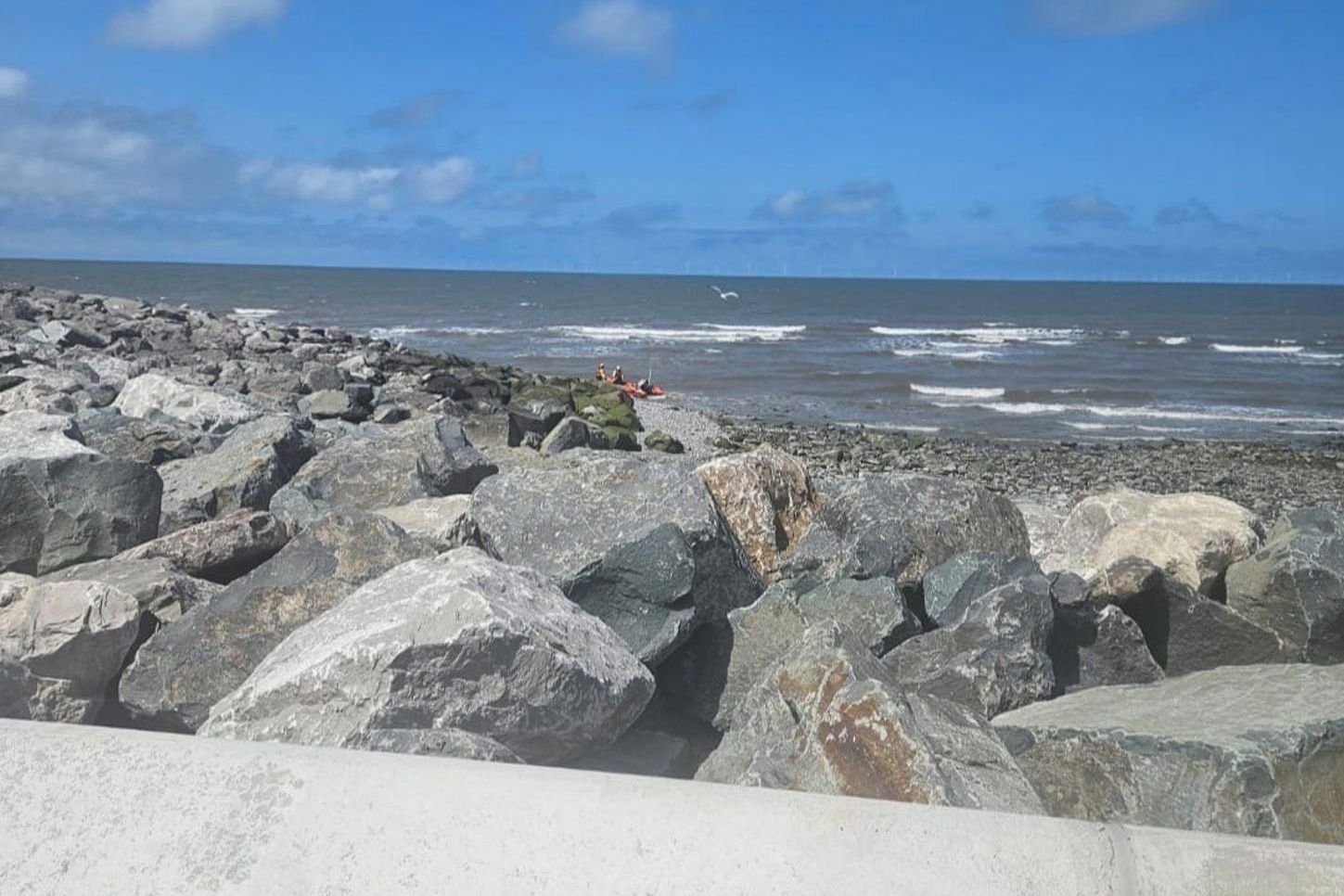 Una costa rocosa con grandes rocas y olas rompiendo sobre la playa.