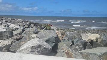 Una costa rocosa con grandes rocas y olas rompiendo sobre la playa.