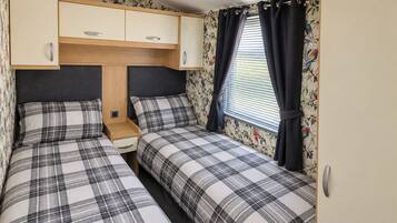 Un dormitorio con dos camas, un armario de madera y una ventana con cortinas.