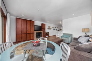 A living room with a sofa, a dining table with chairs, a TV, and a fireplace. - Grandview #615  Waterfront Chelan Condo (Chelan)