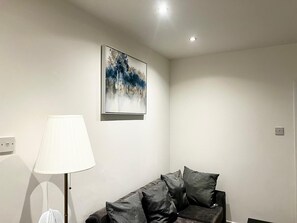 A modern living room with a grey sofa, a white lamp, and a framed abstract painting on the wall. - Apartment Sleeps 4 with Parking (Croydon)