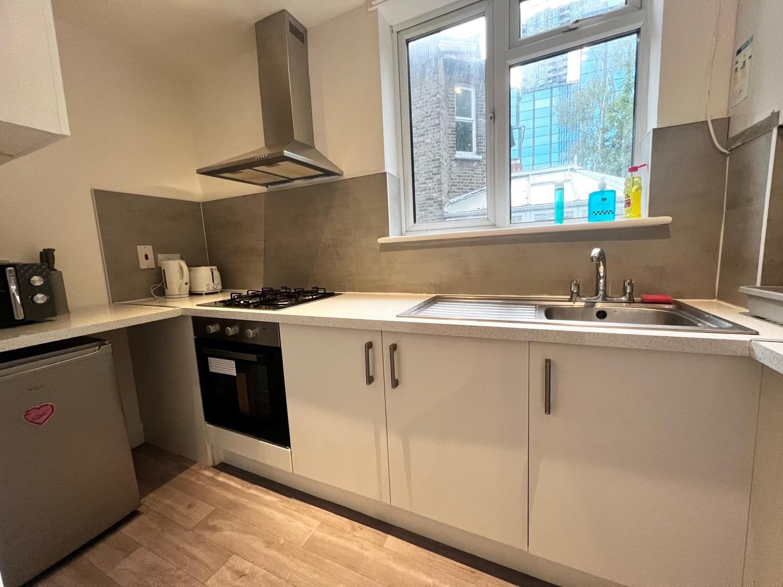 A modern kitchen with a gas stove, oven, and a window above the sink.