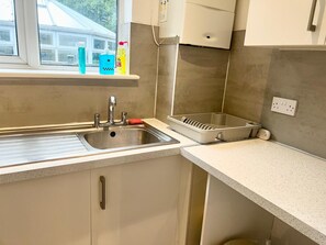 A kitchen with a stainless steel sink, a window above it, and a countertop with a dish rack. - Apartment Sleeps 4 with Parking (Croydon)