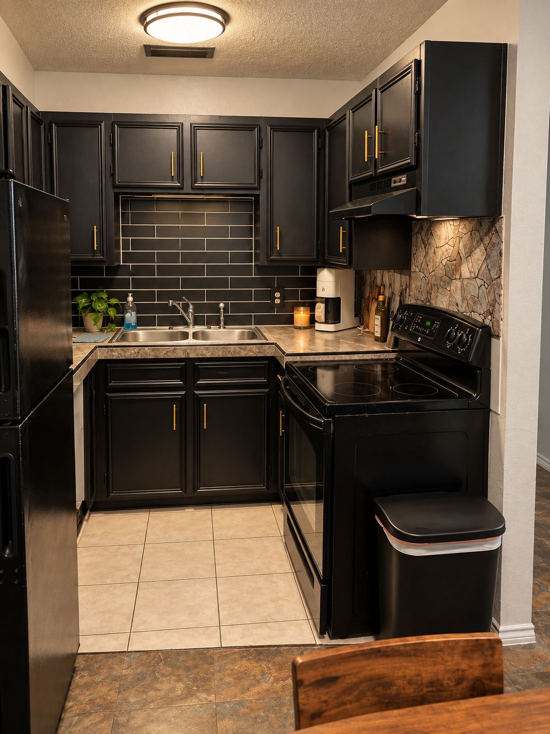 A modern kitchen with black cabinetry, a stainless steel sink, a coffee maker, and a stove.