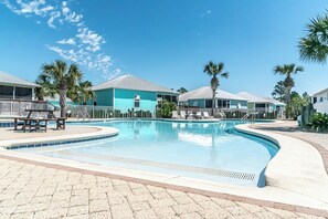 A swimming pool with lounge chairs and palm trees, surrounded by buildings with a light blue exterior. - Rookery 3 6015 Serinerty Calling (Gulf Shores)