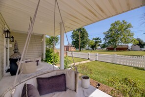 A covered porch with a swing chair, a potted plant, and a decorative lantern. - Marina View Cambridge Cottage: House on Water (Cambridge)