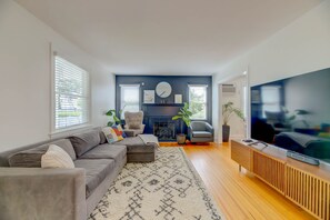 A modern living room with a sectional sofa, a fireplace, a television, and a large window. - Marina View Cambridge Cottage: House on Water (Cambridge)