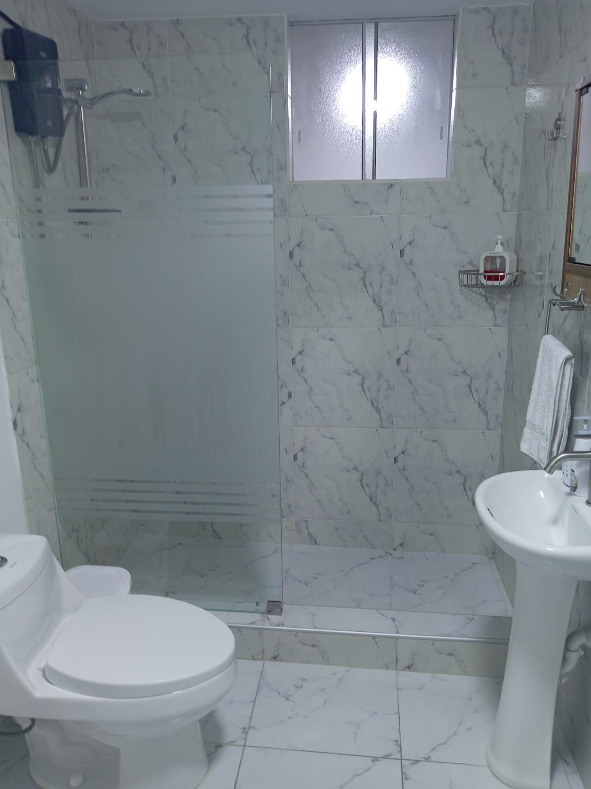 A bathroom with a toilet, sink, and shower area.