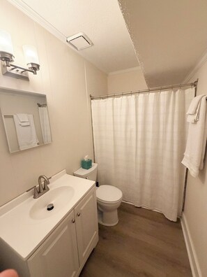 A bathroom with a white sink, toilet, and shower curtain. - Perfect gameday apartment in downtown Athens! (Athens)