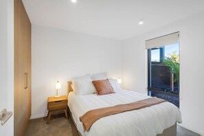 A bedroom with a bed, bedside tables, a window, and a door. - Wananavu | Tathra Escape (Tathra)