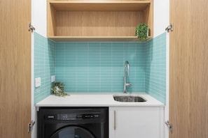 A compact kitchen with a dishwasher, a sink, and a small shelf with a plant. - Wananavu | Tathra Escape (Tathra)