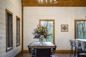 A dining area with a wooden table, chairs, and a floral centerpiece. - Hot Tub + Game Room + Playground | Sleeps 14 (Broken Bow)