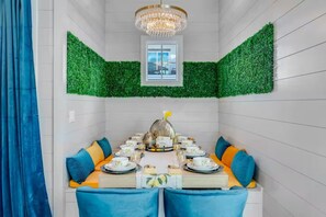A dining area with a table set for four, surrounded by blue upholstered chairs, a chandelier, and green wall decor. - Beach Access • Golf Cart • Sauna+ColdPlunge • Pool (Santa Rosa Beach)