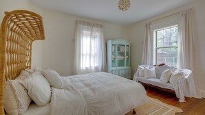 A bedroom with a bed, a sofa, a wicker headboard, a cabinet, and a window with curtains. - Summery Southern Home in the Heart of Starland (Savannah)