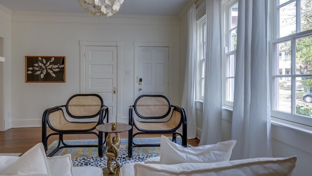 A room with two wicker chairs, a glass table, and a decorative floor lamp. - Summery Southern Home in the Heart of Starland (Savannah)