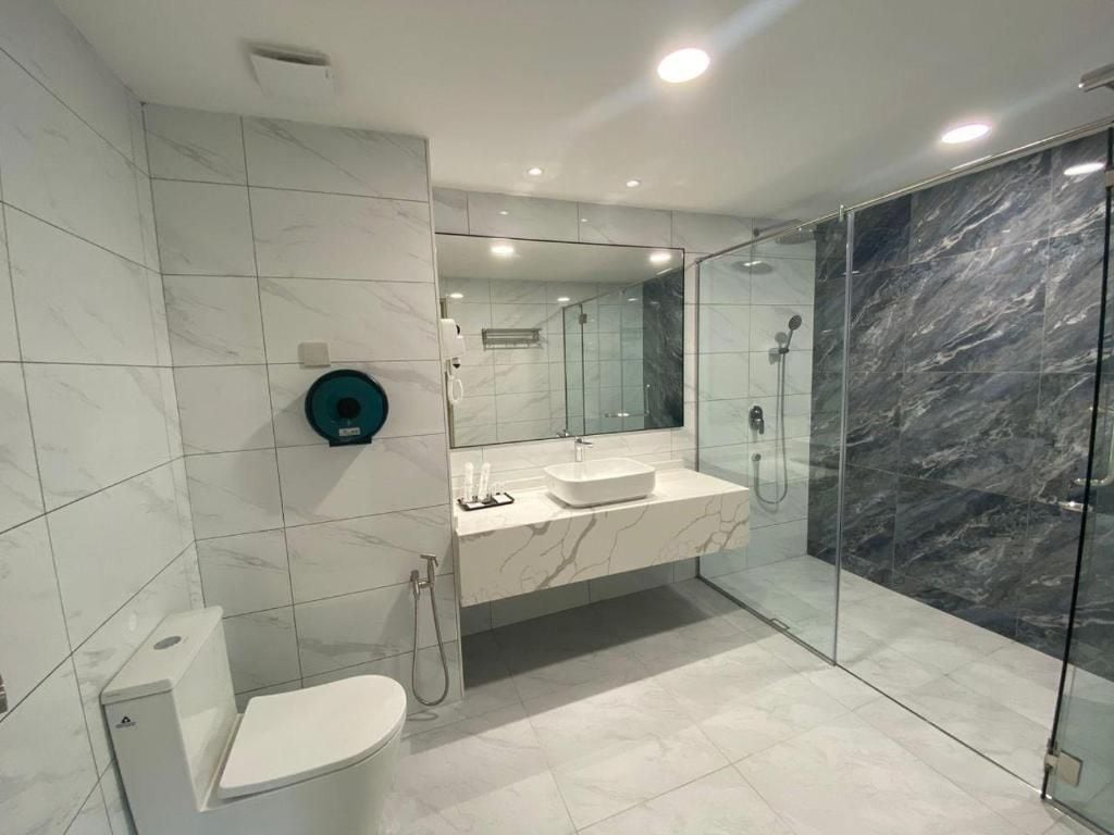 A modern bathroom with a toilet, sink, and glass-enclosed shower area.