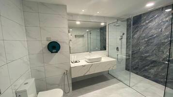 A modern bathroom with a toilet, sink, and glass-enclosed shower area.