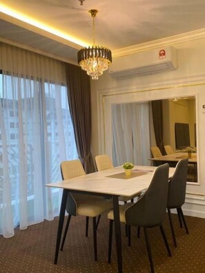 A hotel room with a dining area featuring a table, chairs, and a chandelier.