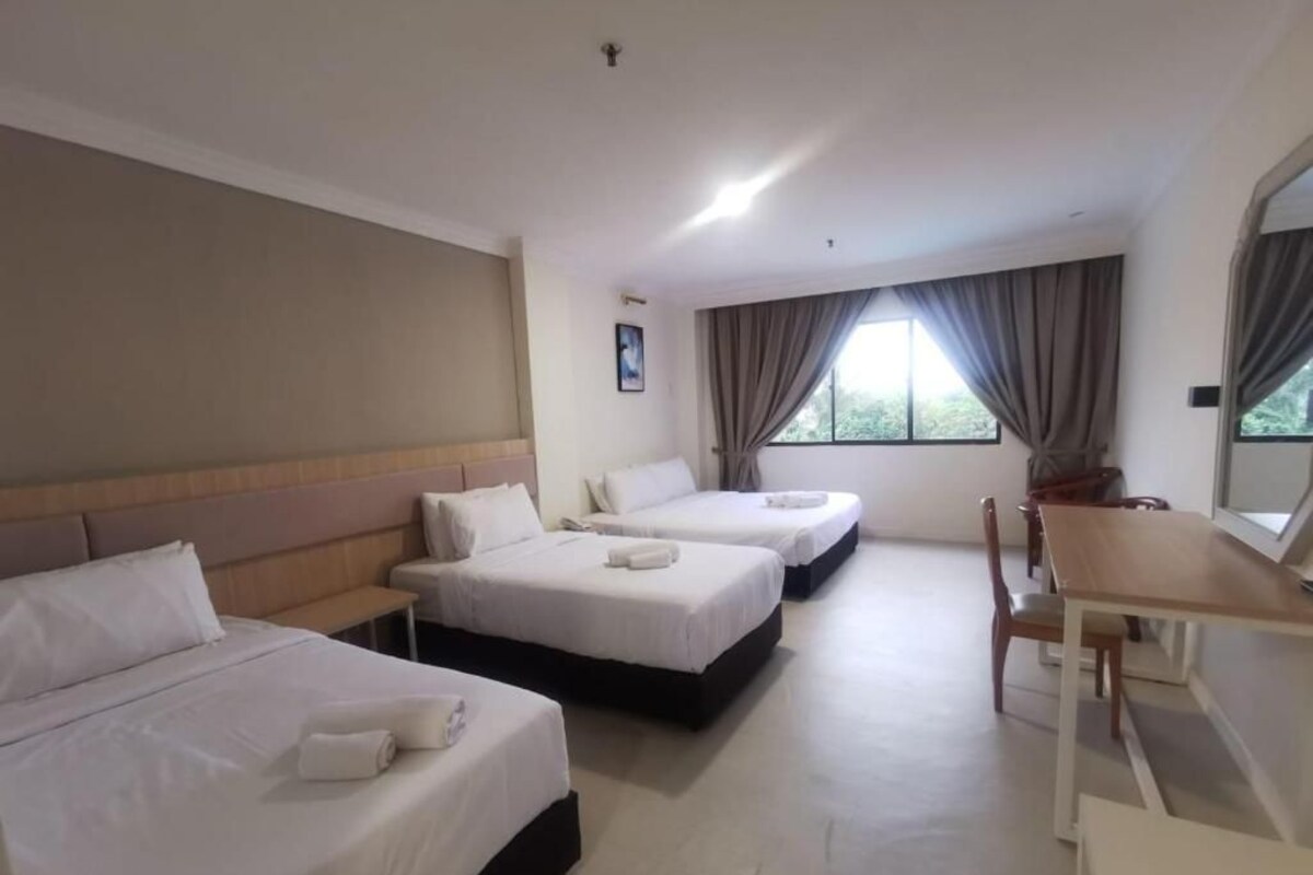 Une chambre d’hôtel avec trois lits, un bureau et une chaise.