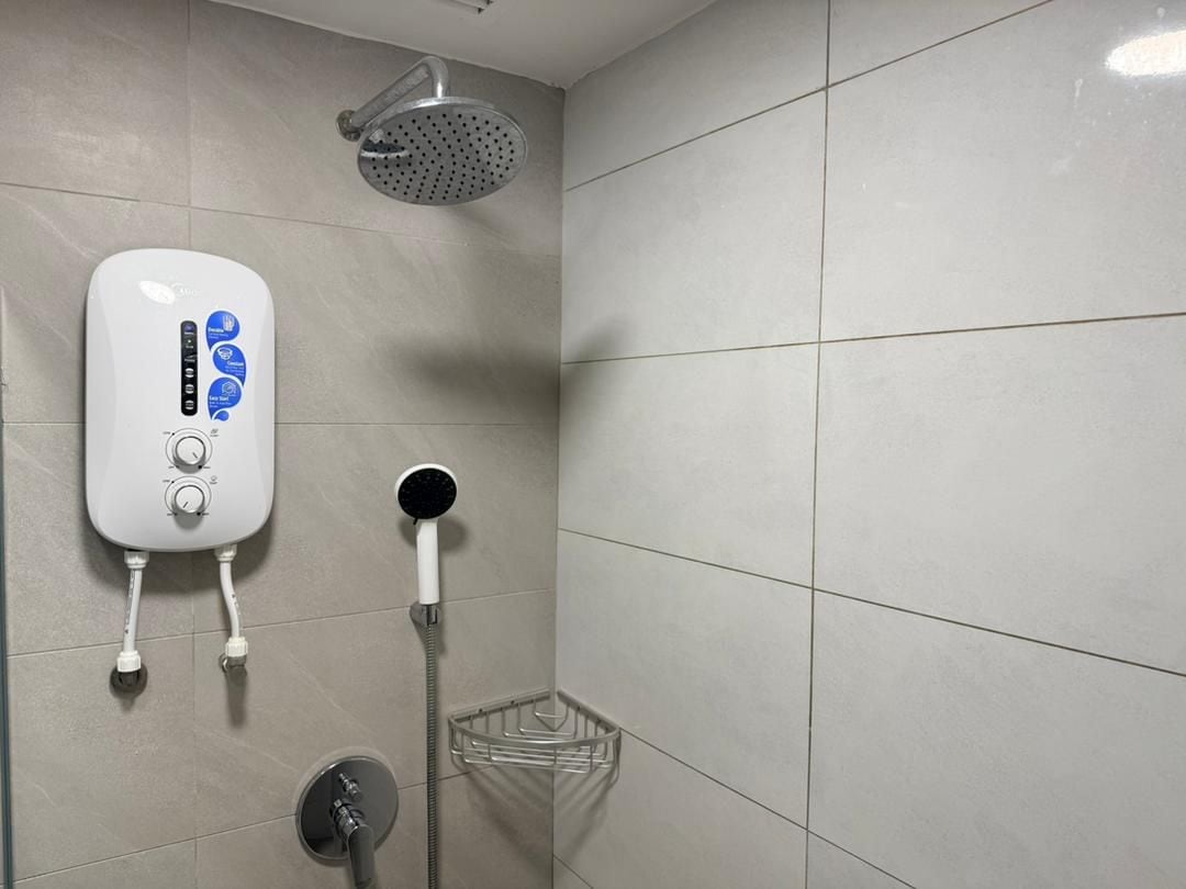 Un baño con ducha de mano, grifo empotrado en la pared y panel de control para la ducha.