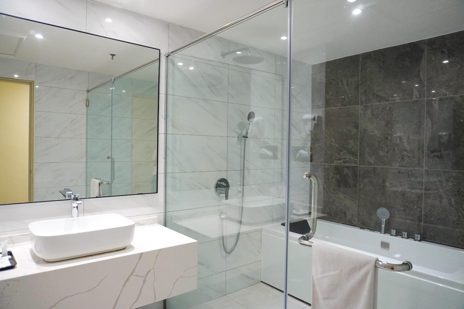 Un baño moderno con ducha envuelta en vidrio, lavamanos blanco y bañera.