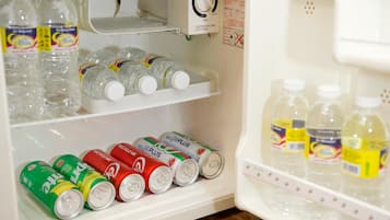 A refrigerator stocked with bottled water, soda cans, and a temperature control dial.