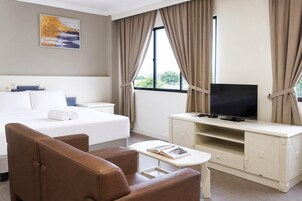 A hotel room with a bed, a TV, a sofa, and a small table.