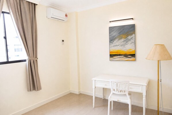 A room with a desk, chair, air conditioning unit, and a lamp.