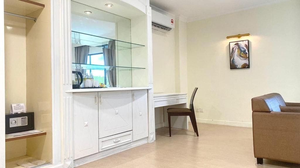 A room with a white cabinet, a glass shelf, a brown chair, and a brown sofa.