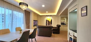 A hotel room with a dining area, a sofa, a television, and a kitchen area.