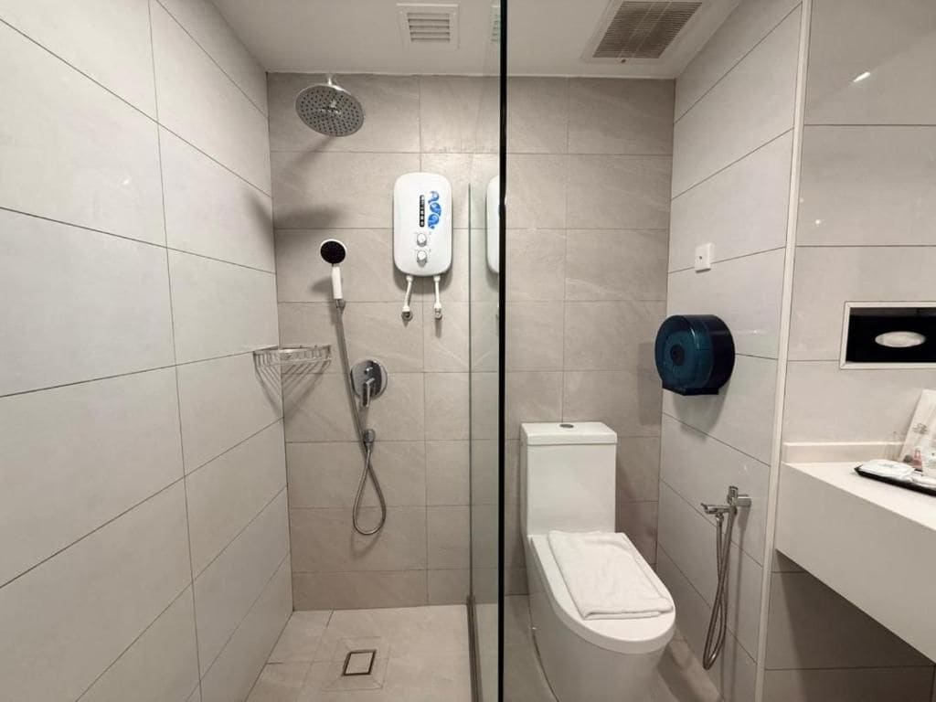A modern bathroom with a glass partition, a shower, a toilet, and a sink.