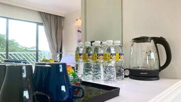 A hotel room with a coffee maker, water bottles, and mugs on a tray.