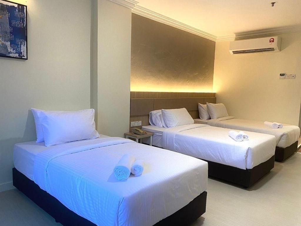 A hotel room with two beds, a nightstand, an air conditioning unit, and a painting on the wall.