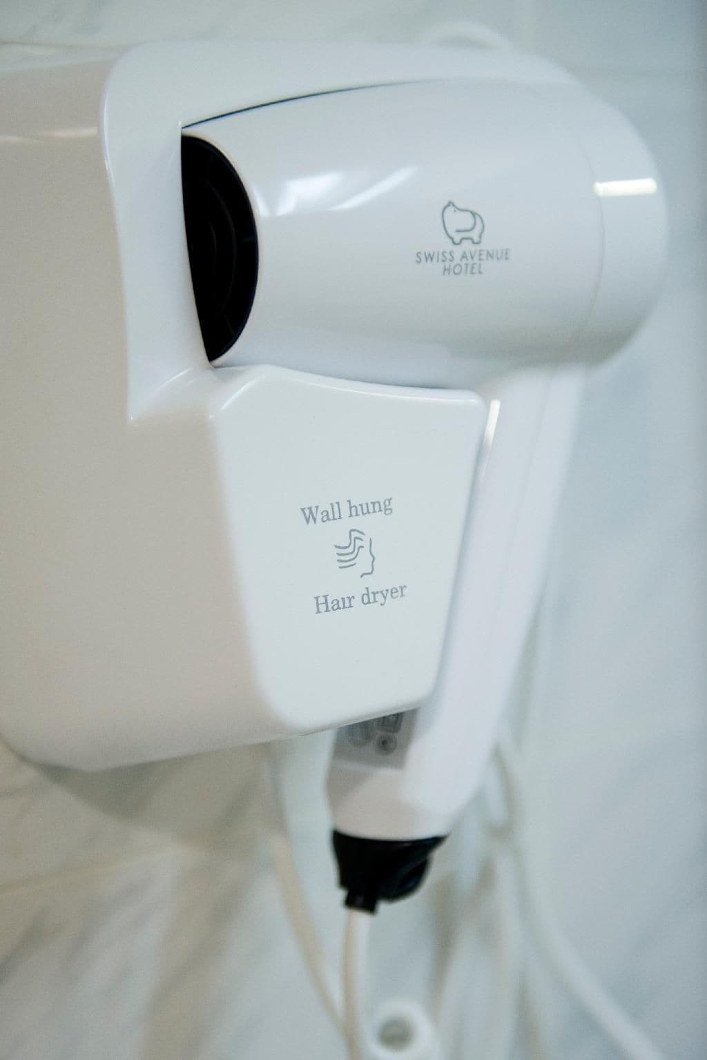 A wall-mounted hair dryer with the text 'Wall hung Hair dryer' and 'SWISS AVENUE HOTEL' visible.