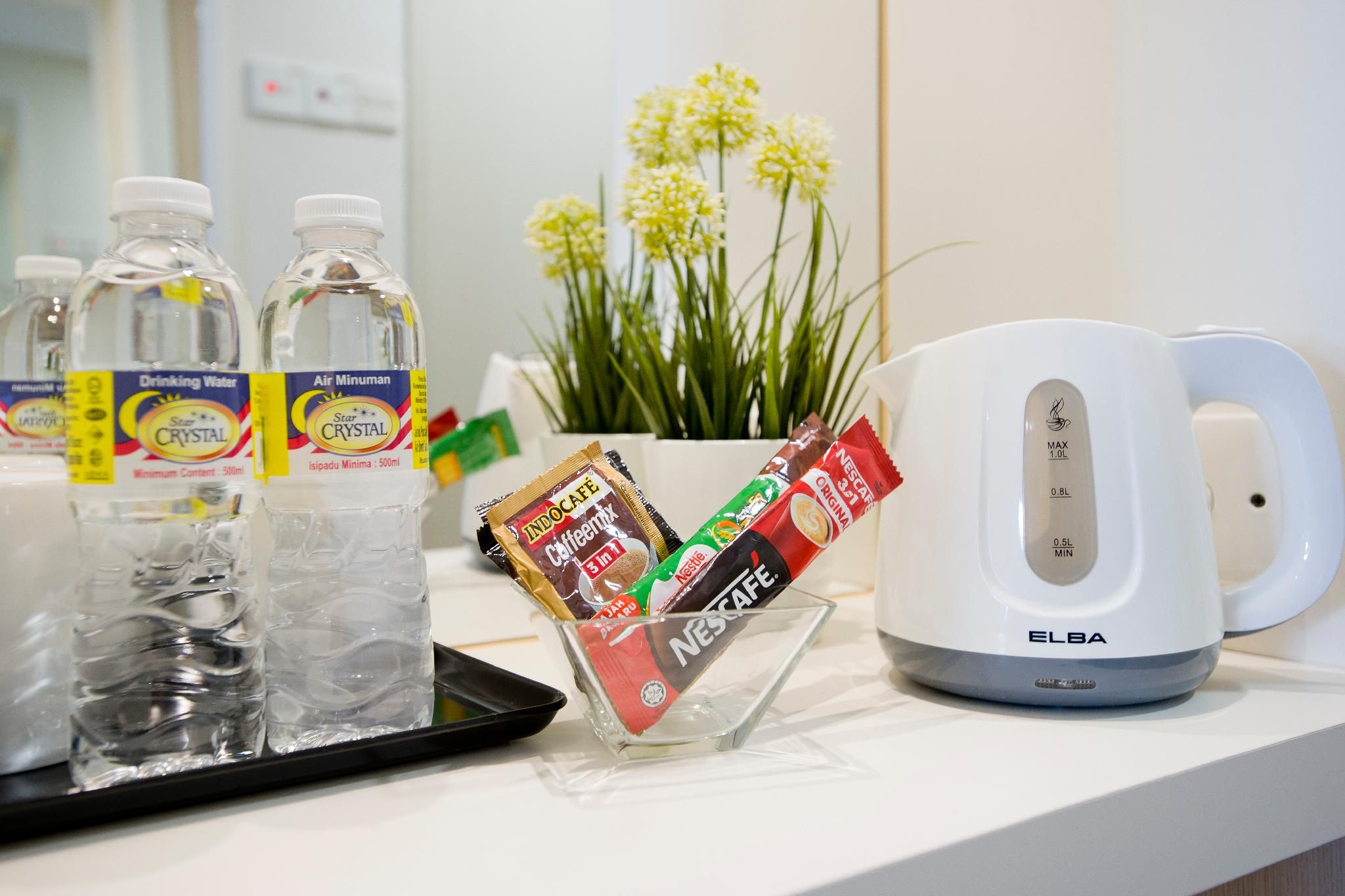 A tray with bottled water, a coffee maker, and a cup of coffee on a hotel counter.