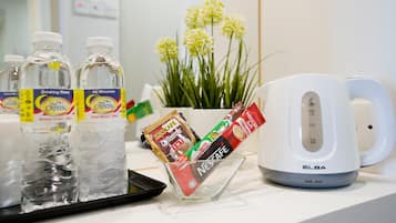 A tray with bottled water, a coffee maker, and a cup of coffee on a hotel counter.