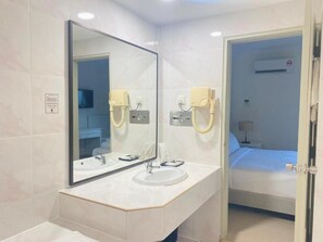Une salle de bain moderne avec un grand miroir, deux lavabos et un espace douche.