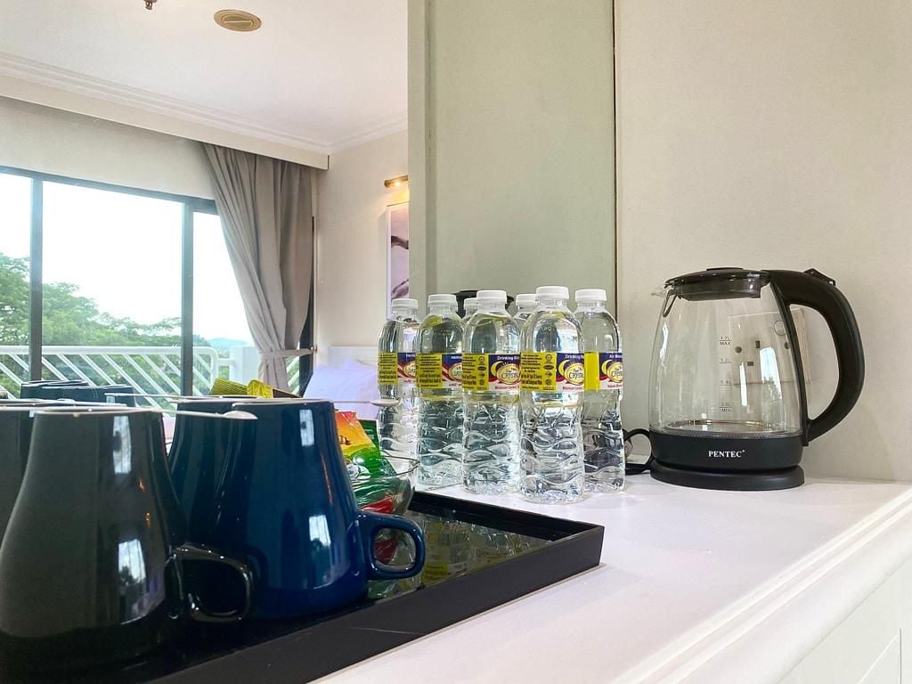 A hotel room with a coffee maker, water bottles, and mugs on a tray.