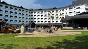 A hotel courtyard with a swimming pool, outdoor seating, and a large building with multiple floors and air conditioning units. - SWISS AVENUE HOTEL SUNGAI PETANI  (Sungai Petani)