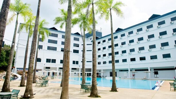 A multi-story hotel with a swimming pool, surrounded by palm trees. - SWISS AVENUE HOTEL SUNGAI PETANI  (Sungai Petani)