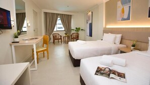A hotel room with two beds, a desk, a chair, and a small table. - SWISS AVENUE HOTEL SUNGAI PETANI  (Sungai Petani)