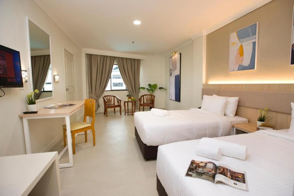 Une chambre d’hôtel avec deux lits, un bureau, une chaise et une petite table.