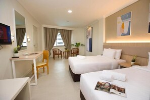 Une chambre d’hôtel avec deux lits, un bureau, une chaise et une petite table.