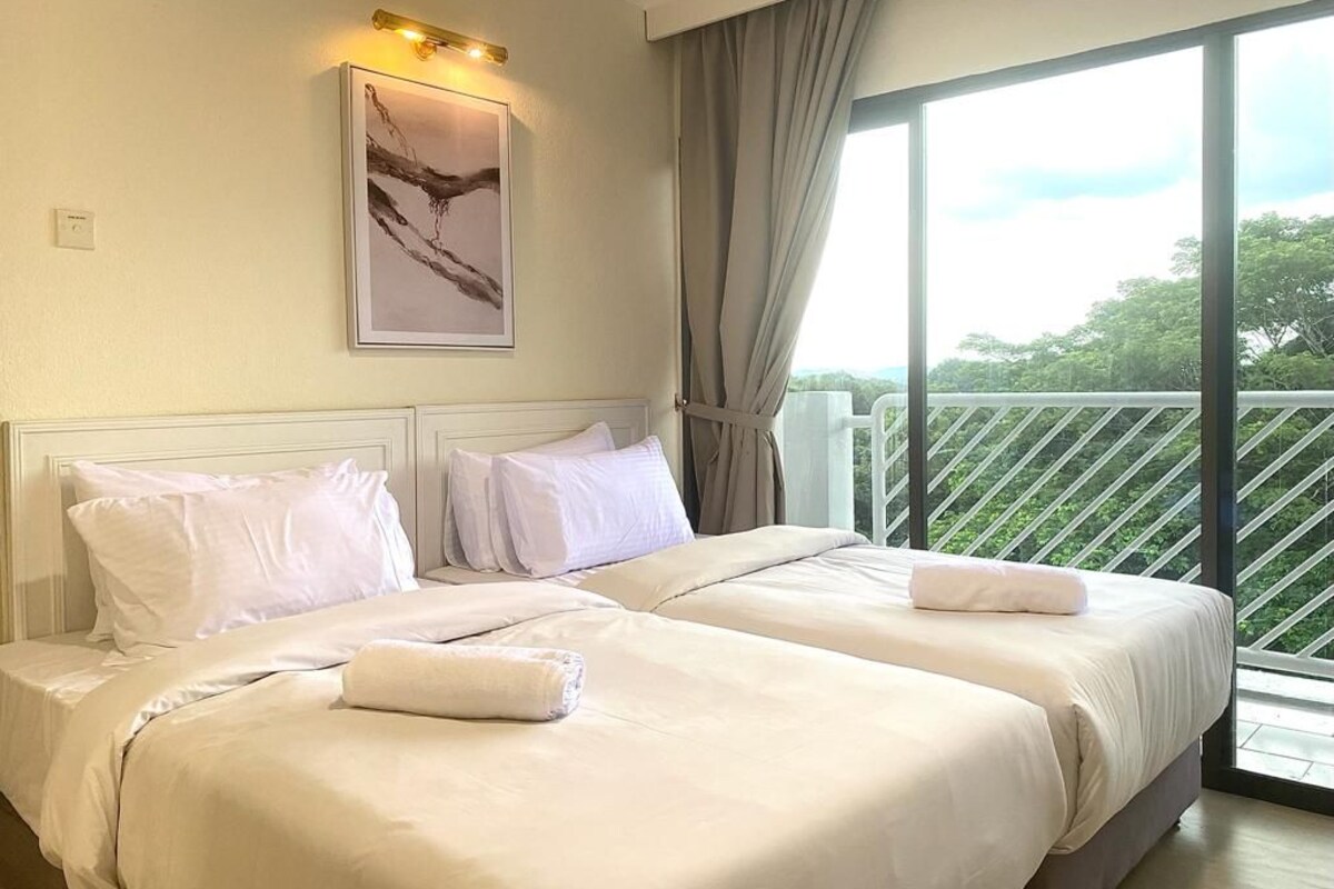 Une chambre d’hôtel avec deux lits, une grande fenêtre donnant sur un paysage verdoyant et un tableau accroché au mur.