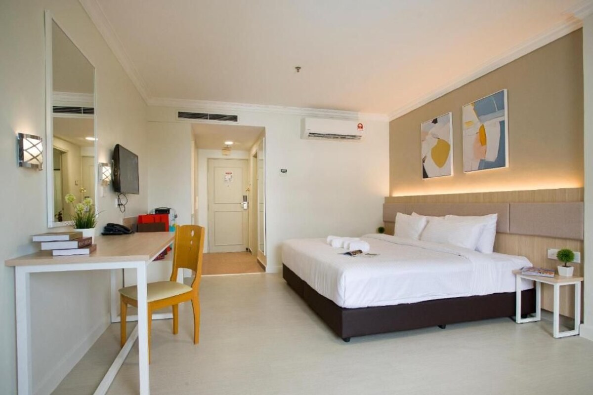 Une chambre d’hôtel équipée d’un lit, d’un bureau, d’une chaise, d’une télévision et d’œuvres d’art accrochées au mur.