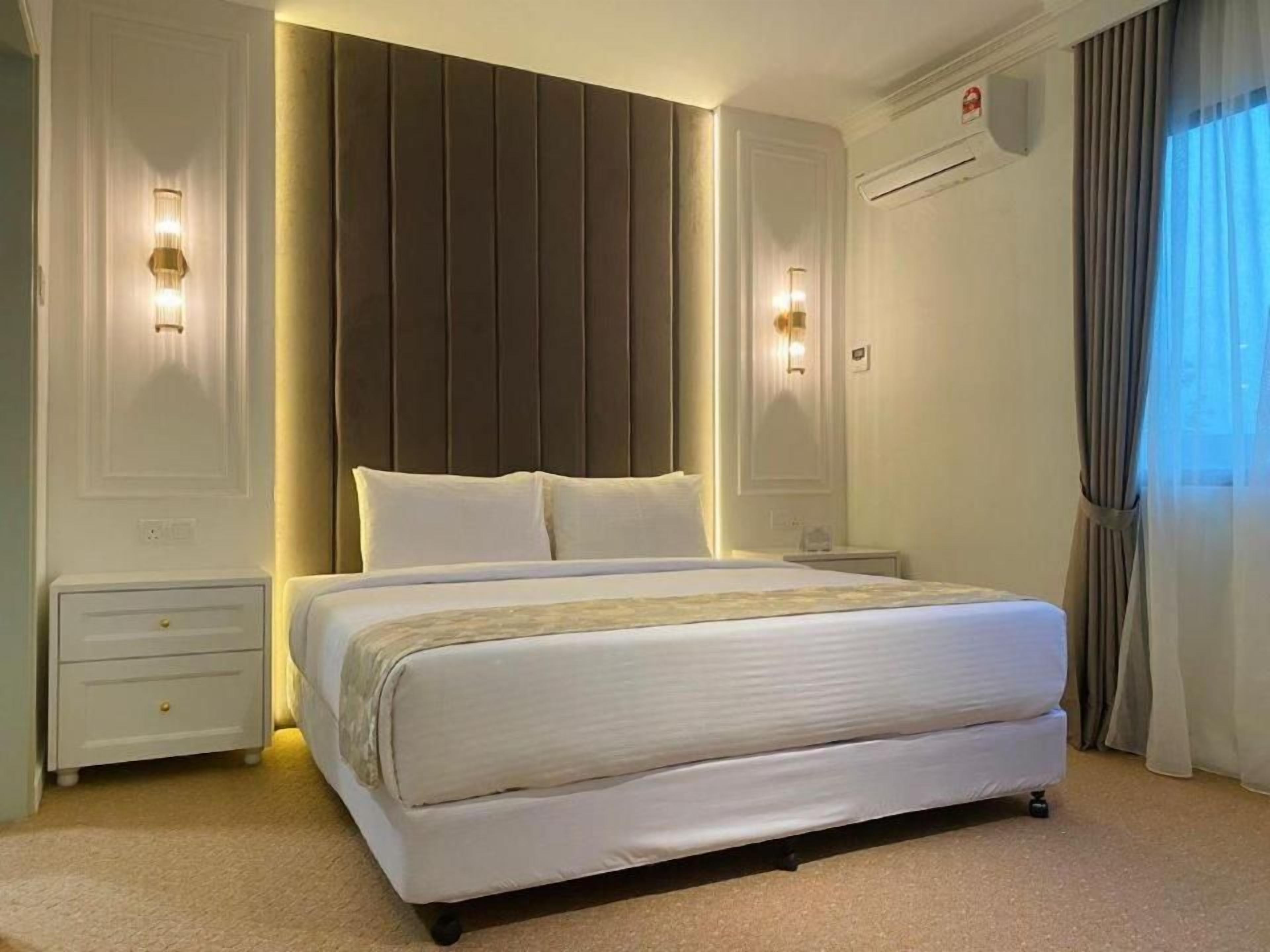 A hotel room with a large bed, bedside lamps, a nightstand, and a window with curtains.