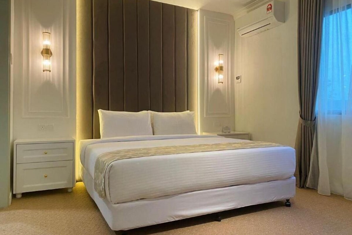 Une chambre d’hôtel avec un grand lit, des lampes de chevet, une table de nuit et une fenêtre avec des rideaux.